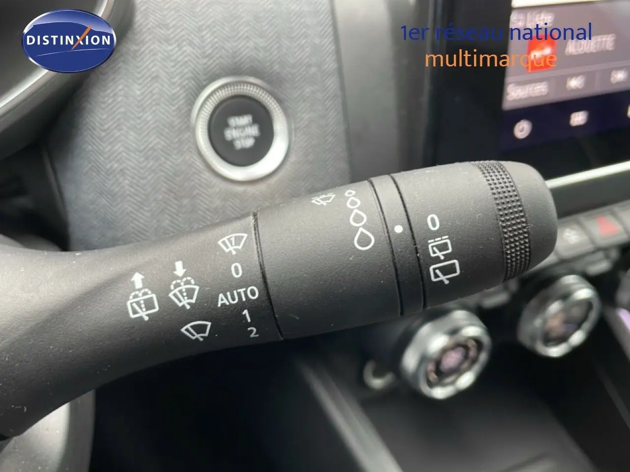 Gros plan sur la commande d’essuie-glace de la Renault Clio gris schiste, avec bouton start et console en arrière-plan flou.