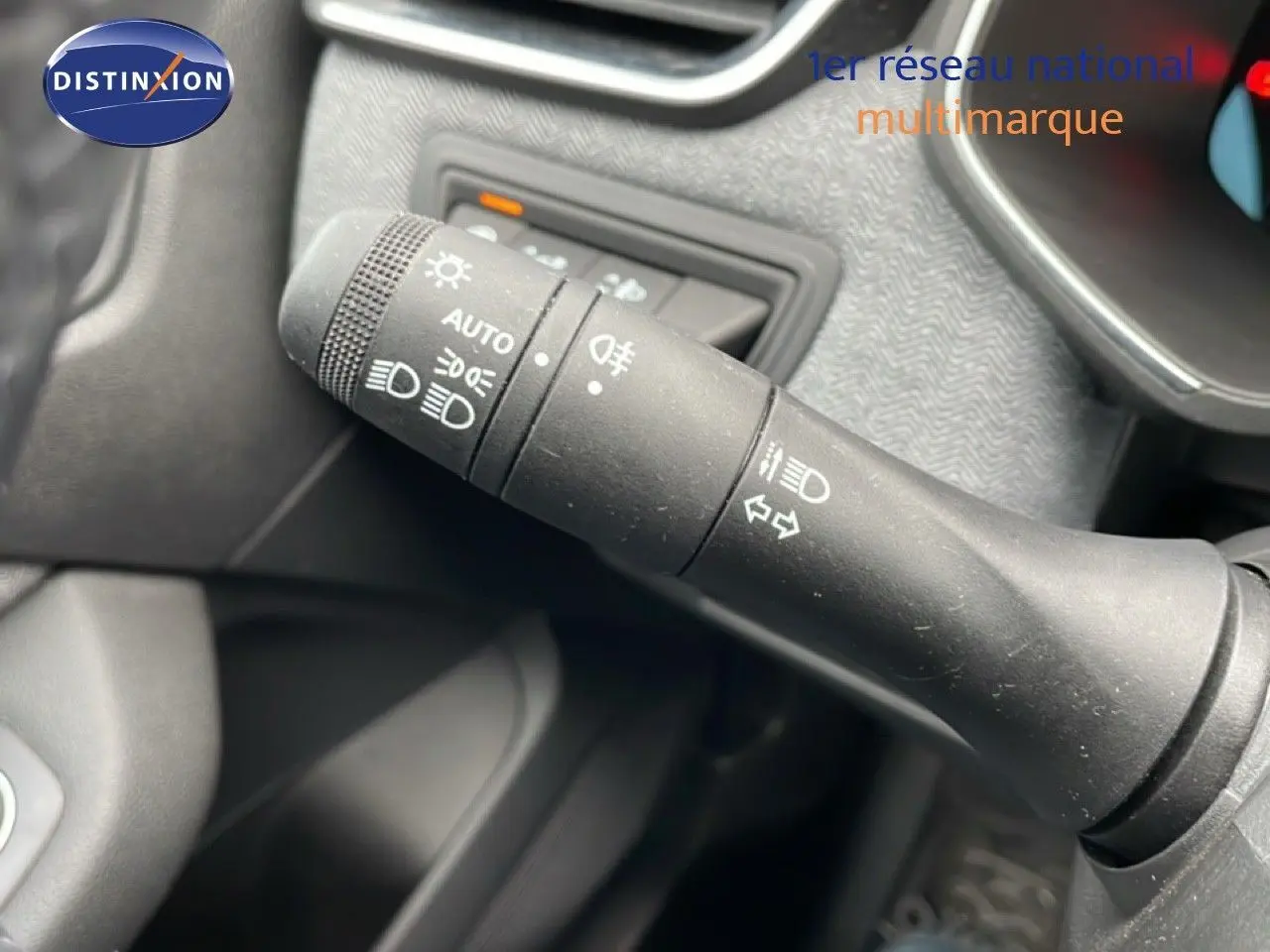 Gros plan sur la commande des feux et clignotants à gauche du volant dans l'habitacle d'une Renault Clio gris schiste.