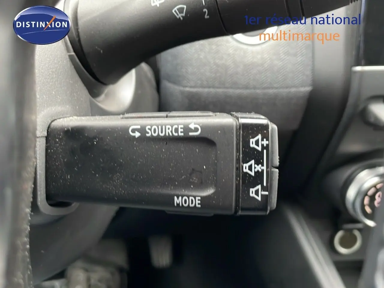 Gros plan sur la commande au volant gauche de la Renault Clio gris schiste, avec boutons source et mode visibles.