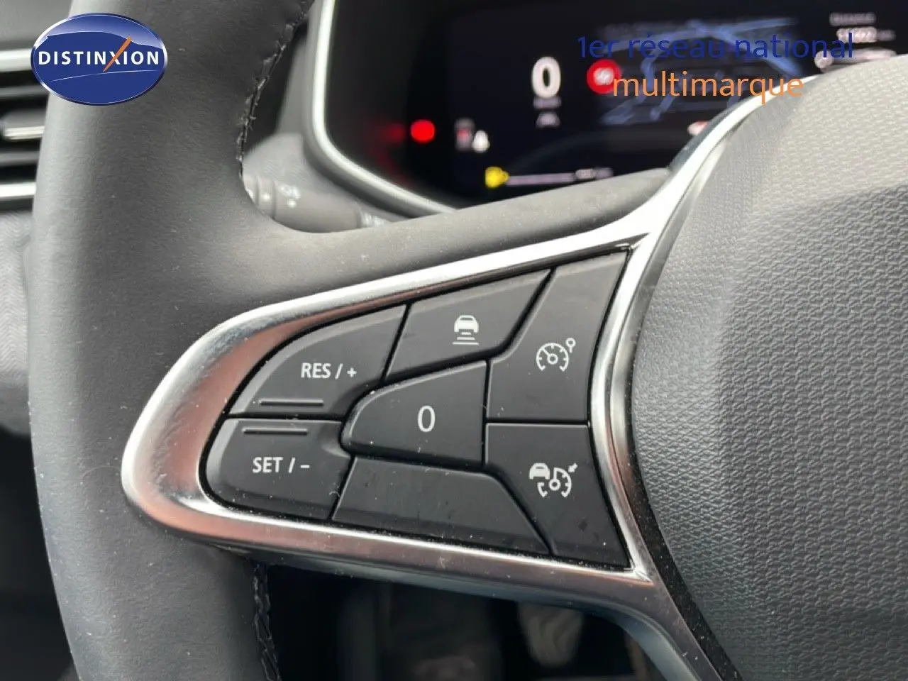 Gros plan sur les commandes au volant côté gauche de la Renault Clio 2025 gris schiste métal avec régulateur de vitesse.