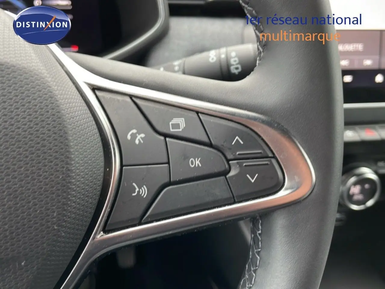 Gros plan sur les commandes multifonctions à droite du volant cuir noir de la Renault Clio gris schiste métal 2025.