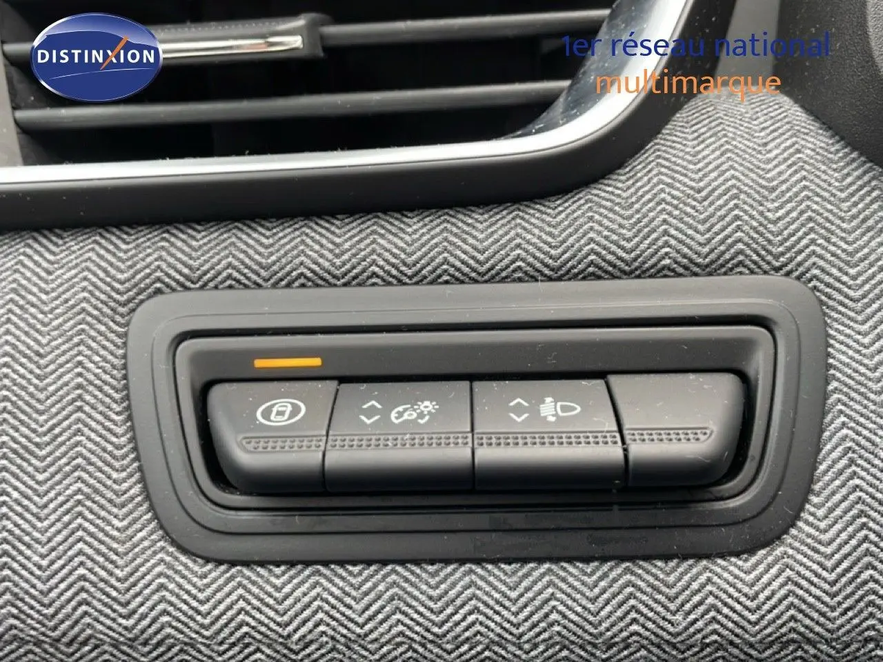 Gros plan sur les commandes d’éclairage et réglages intérieurs de la Renault Clio 2025, tissu gris à chevrons visible.