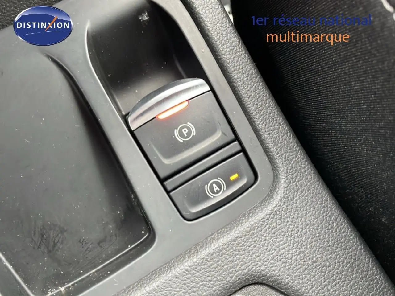 Gros plan sur les commandes de frein à main et arrêt automatique du moteur dans une Renault Clio gris schiste métal, intérieur noir.