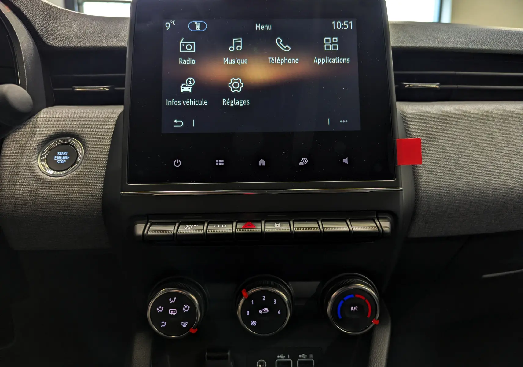 Vue rapprochée de la console centrale de la Renault Clio V 2025, écran tactile et commandes climatisation visibles.