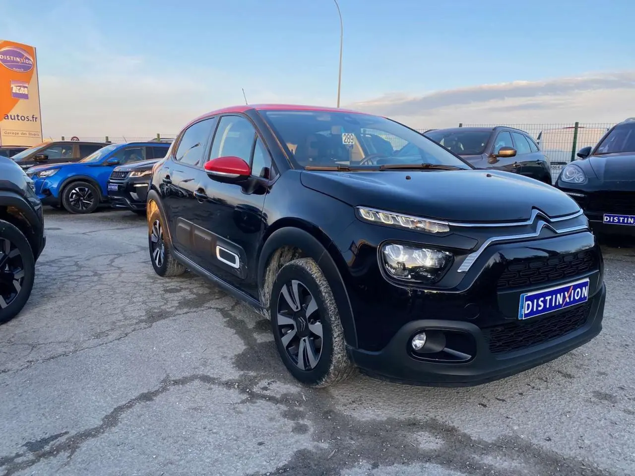 Citroën C3 Shine 2023 noir avec toit et rétroviseurs rouges, vue 3/4 avant droit en extérieur.