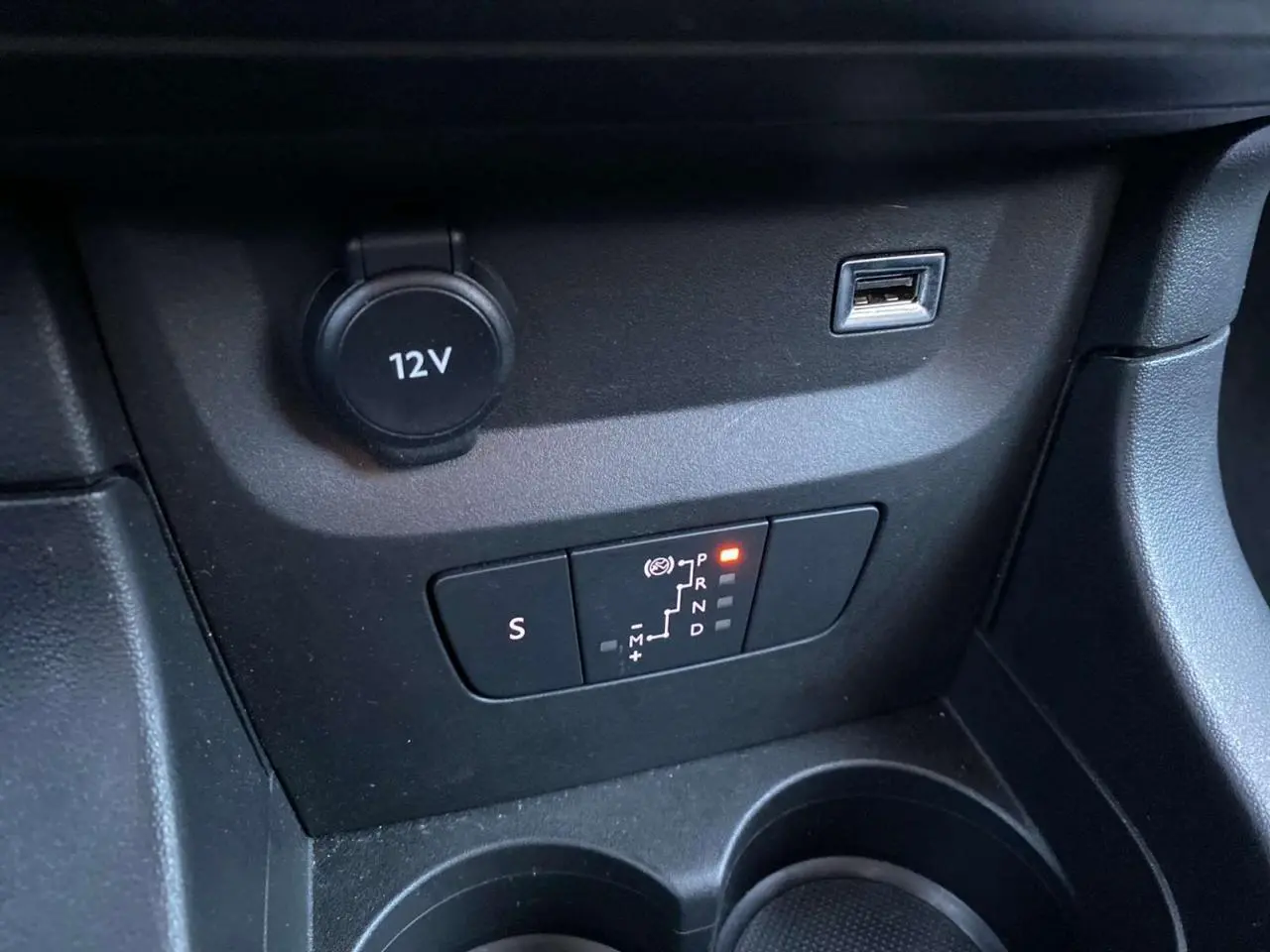 Gros plan sur la commande de boîte automatique et prise 12V dans l’habitacle noir de la Citroën C3 Shine 2023.