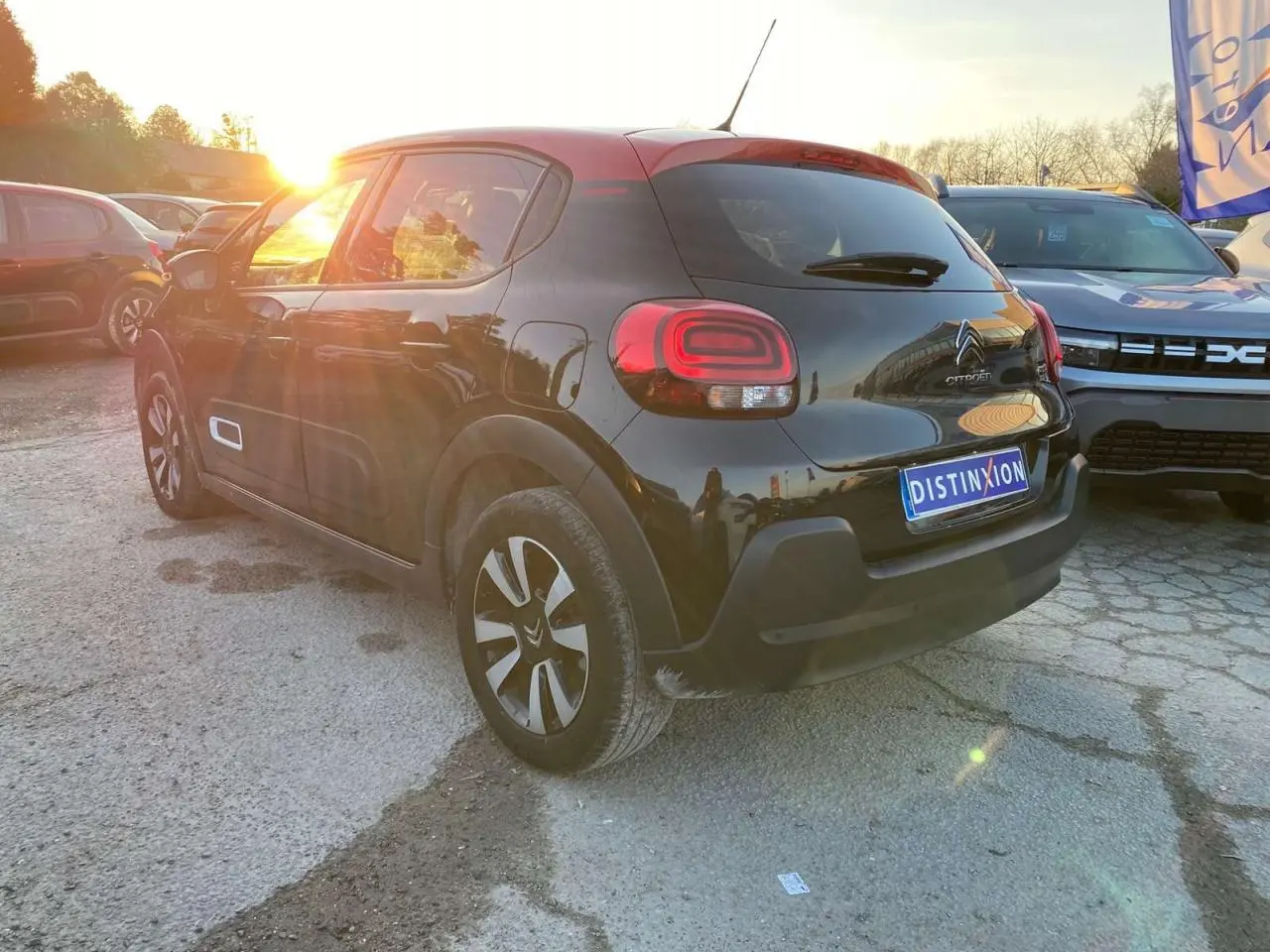 Citroën C3 Shine 2023 noir toit rouge, vue 3/4 arrière droit au coucher de soleil avec jantes alliage diamantées.
