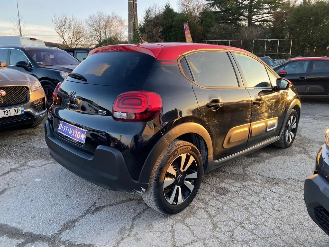 Vue 3/4 arrière droite d'une Citroën C3 2023 noire avec toit rouge et jantes alliage diamantées.
