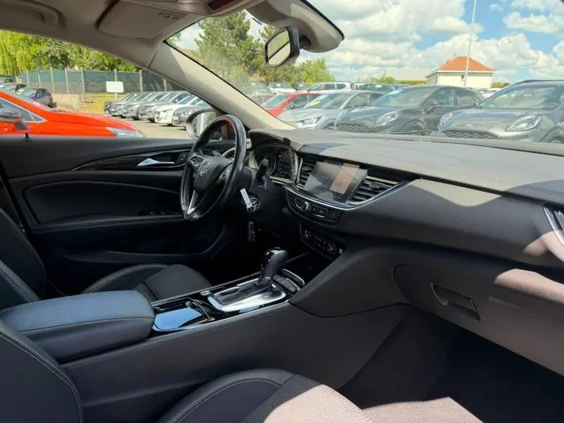 Vue intérieure côté conducteur de l'Opel Insignia Grand Sport 2021 avec tableau de bord noir et console centrale brillante.
