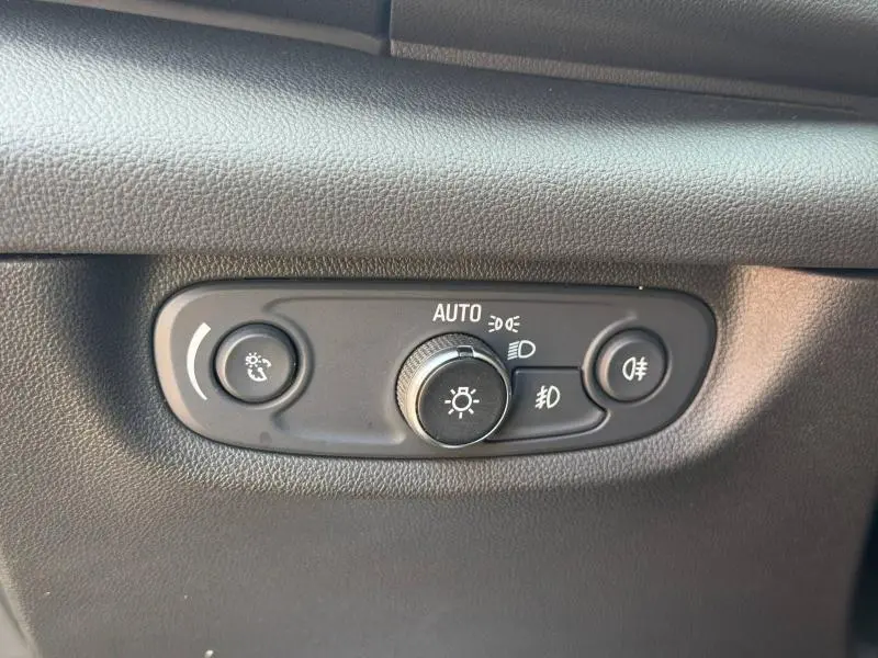 Gros plan sur le panneau de commande des phares de l’Opel Insignia Grand Sport, intérieur noir texturé.