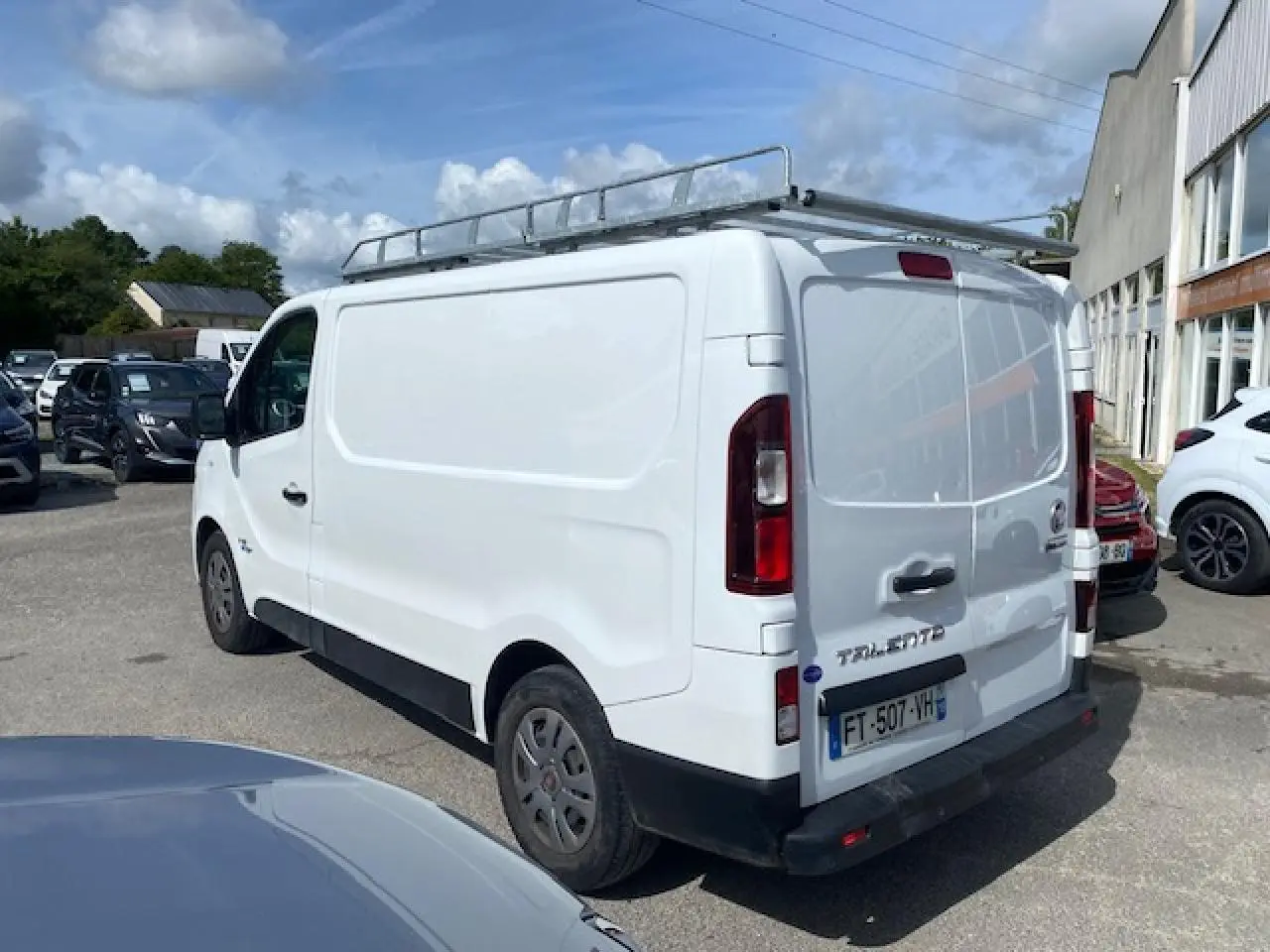 Vue 3/4 arrière droite d’un FIAT Talento Fourgon blanc avec galerie de toit et portes arrière tôlées ouvertes à 180°.