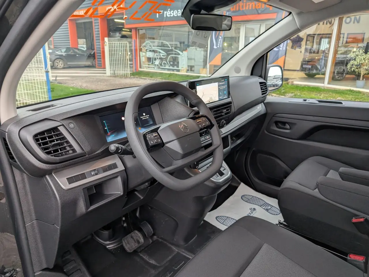 Vue intérieure côté conducteur du Citroën Jumpy XL 2025, tableau de bord noir avec écran tactile et volant multifonction.