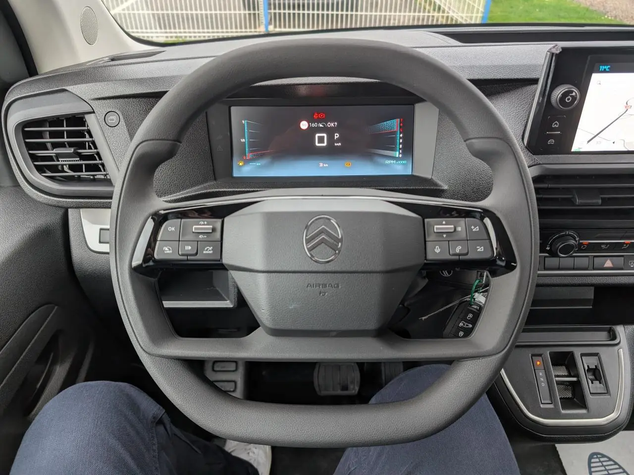 Vue intérieure centrée sur le volant carré noir et le combiné numérique du Citroën Jumpy XL 2025 gris.