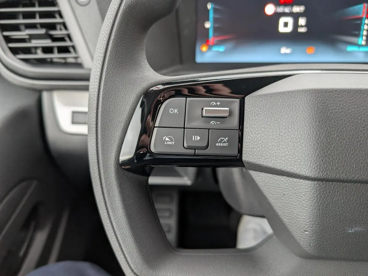 Gros plan sur les commandes gauche du volant gris du Citroën Jumpy XL 2025 avec écran numérique en arrière-plan.