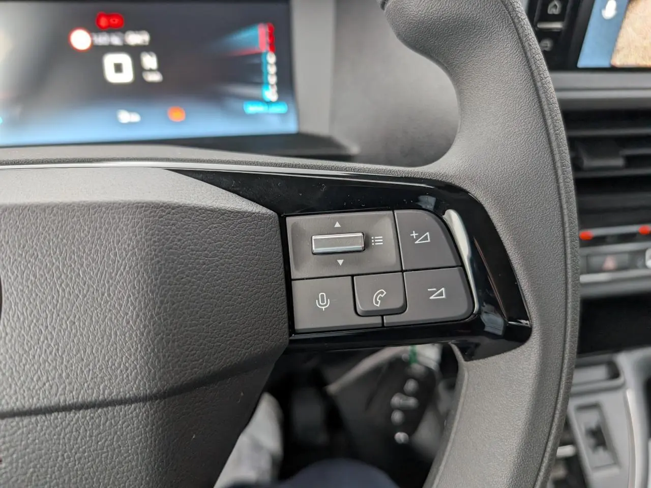Gros plan sur les commandes audio et téléphone au volant du Citroën Jumpy gris, côté gauche.