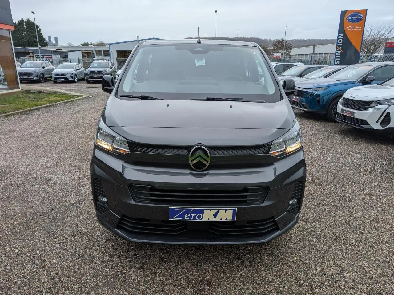 Vue avant d’un Citroën Jumpy XL gris avec phares allumés sur un parking extérieur.