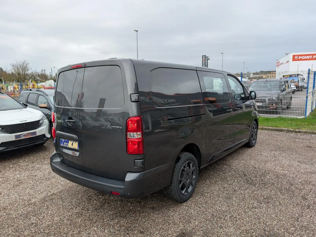 Vue 3/4 arrière droite d’un Citroën Jumpy XL gris métallisé avec boucliers teintés et vitres arrière surteintées.