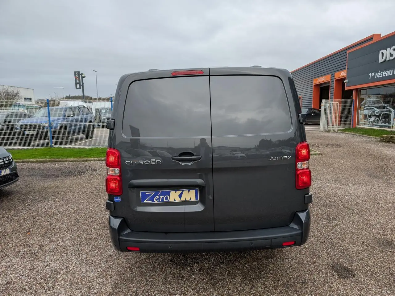 Vue arrière d’un Citroën Jumpy gris 2025 avec portes battantes et bouclier arrière demi-peint noir.