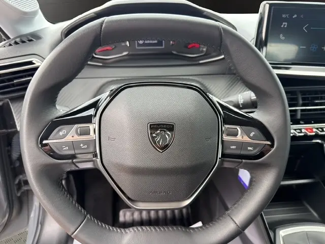 Volant cuir noir de Peugeot 208 100CH S&S Active 2024, vue frontale centrée sur commandes multifonctions et logo lion.