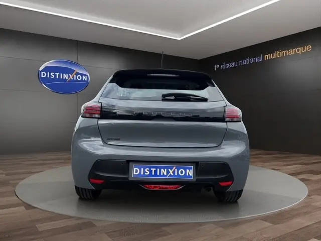 Vue arrière d'une Peugeot 208 gris foncé 2024, avec feux LED et logo distinctif sur un podium intérieur.