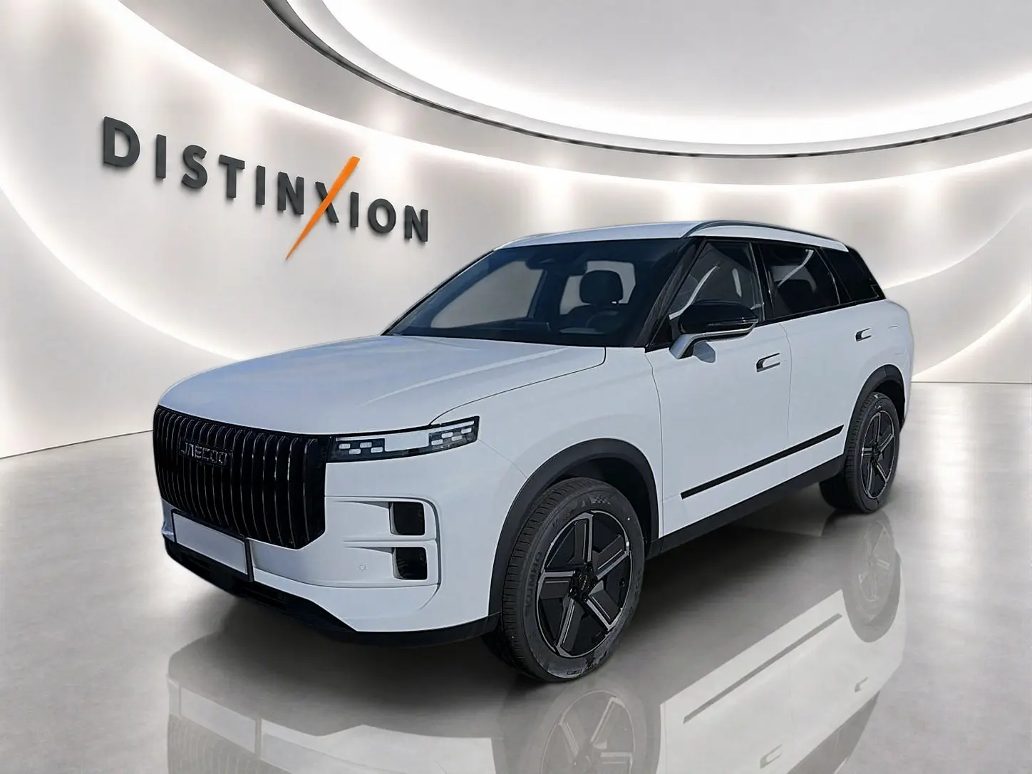 Vue 3/4 avant du SUV JAECOO J7 blanc kaki avec toit noir et calandre verticale noire dans un showroom lumineux.