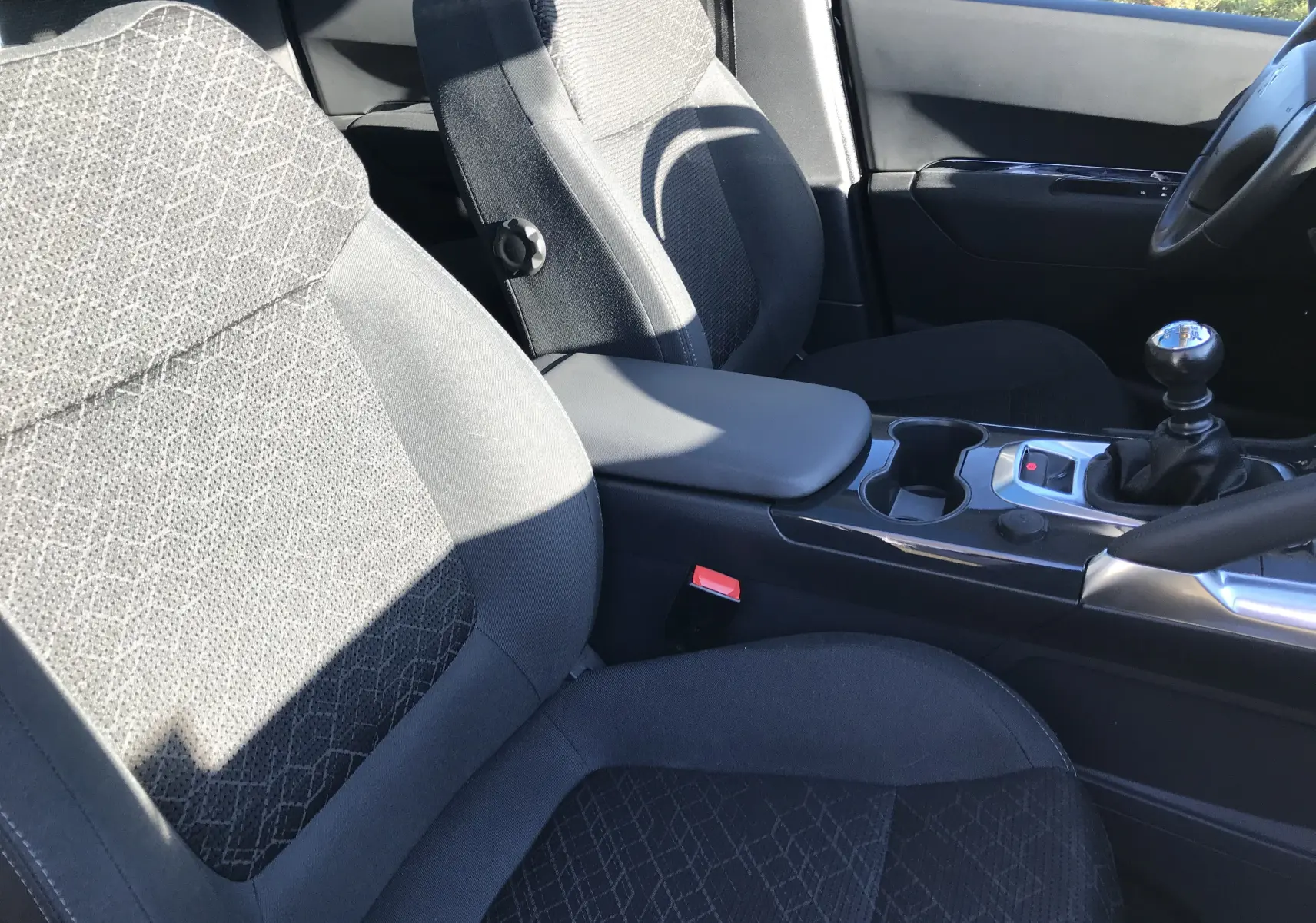 Vue intérieure rapprochée des sièges avant noirs et de la console centrale avec levier de vitesse manuelle du Peugeot 3008 Business bleu Bourrasque 2015.