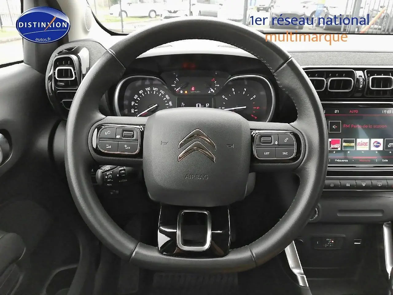 Vue centrée sur le volant noir du Citroën C3 Aircross 2022, avec tableau de bord et écran tactile en arrière-plan.