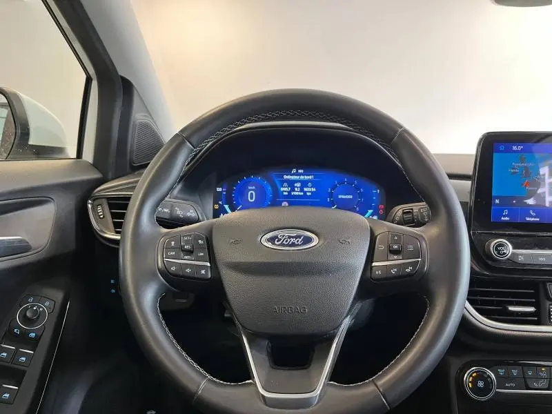 Vue centrée sur le volant multifonction noir et le tableau de bord numérique bleu du Ford Puma blanc Glacier de 2022.