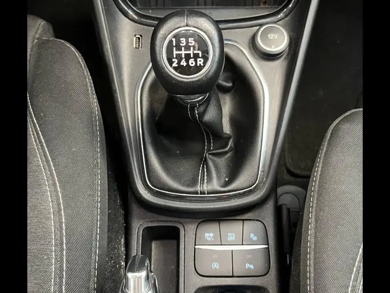 Vue plongeante sur la console centrale noire du Ford Puma blanc, avec boutons de contrôle et levier de vitesse manuel.