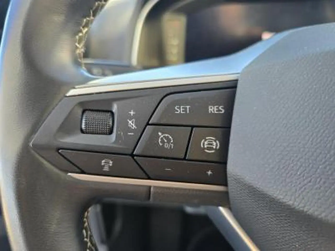 Gros plan sur les commandes du volant cuir multifonction du SEAT Arona 2024, boutons de régulateur de vitesse et assistance.