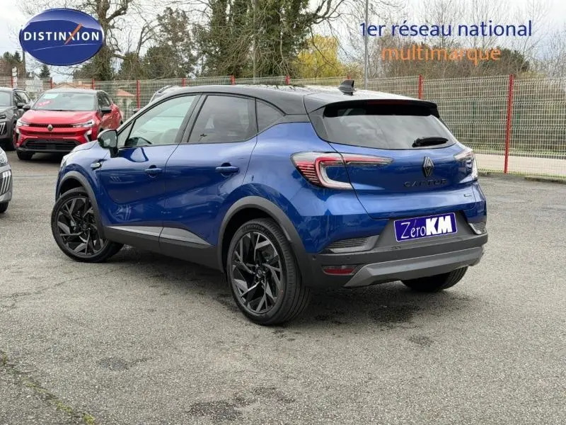 Renault Captur 2026 bleu Iron avec toit noir, vue 3/4 arrière droit, jantes noires et logo Alpine visible.