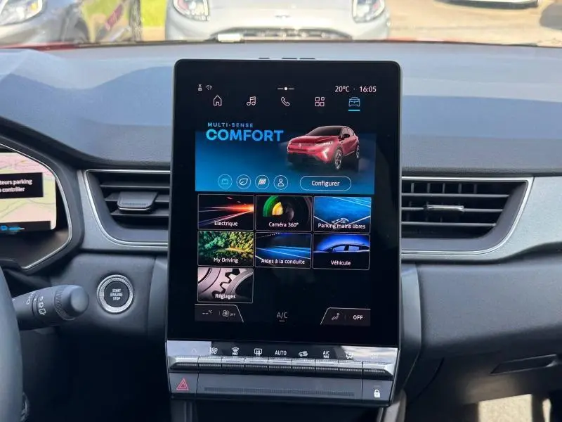 Vue intérieure centrée sur l'écran tactile du tableau de bord du Renault Captur rouge 2025, affichant le mode Confort.