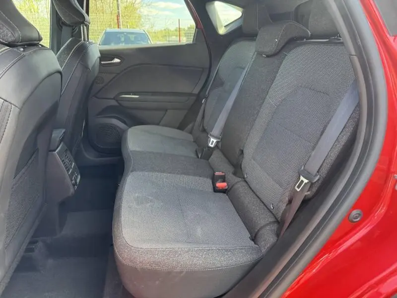 Vue intérieure côté droit sur la banquette arrière grise du Renault Captur rouge 2025 avec ceintures de sécurité visibles.