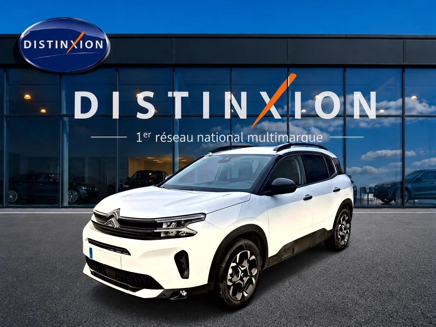 Citroën C5 Aircross blanc vue 3/4 avant droit avec jantes alu et barres de toit noires devant showroom Distinxion.