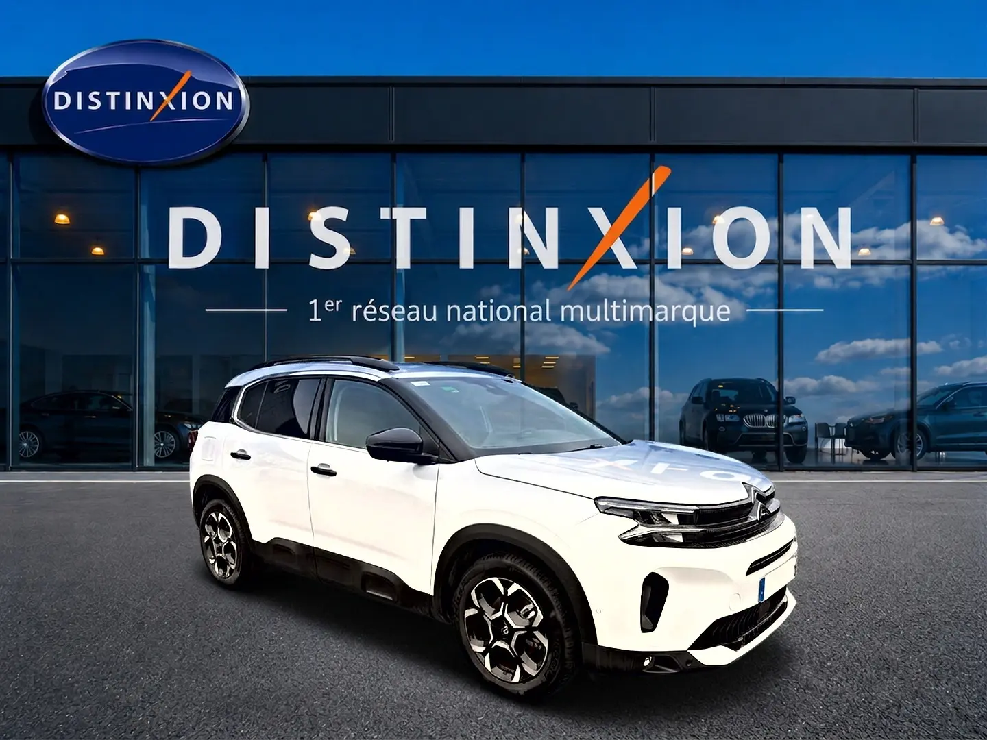 Citroën C5 Aircross blanc vue 3/4 avant droit, avec jantes alu noires et barres de toit visibles.