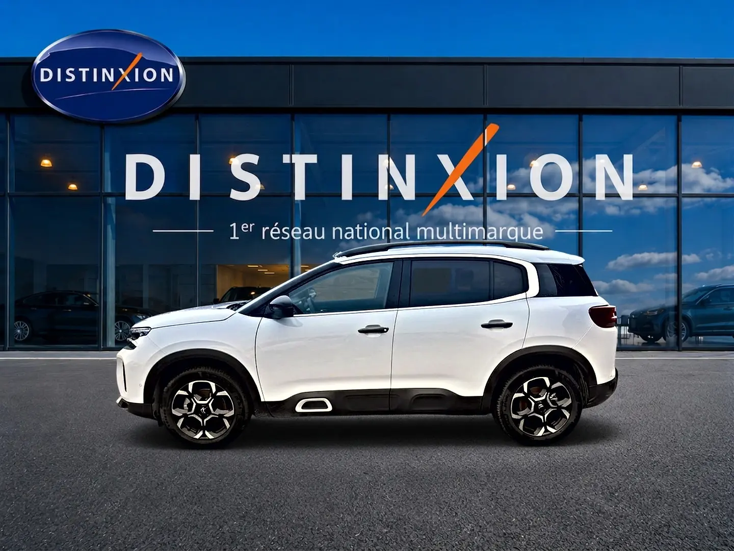 Profil droit du Citroën C5 Aircross blanc 2025 avec jantes alu et barres de toit devant une vitrine Distinxion.