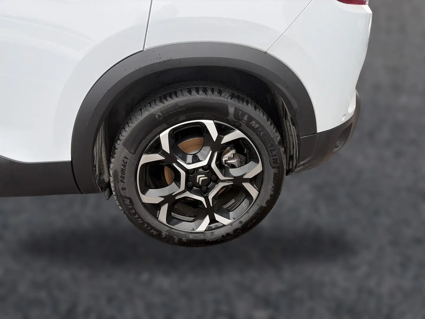 Gros plan sur la roue arrière droite d'un Citroën C5 Aircross blanc avec jante alliage noire et argentée.