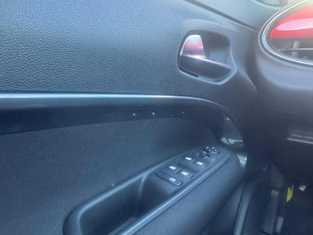 Intérieur côté gauche de la porte FIAT 600 T-Gen 3 rouge 2025, avec commandes de vitres et poignée métallique.