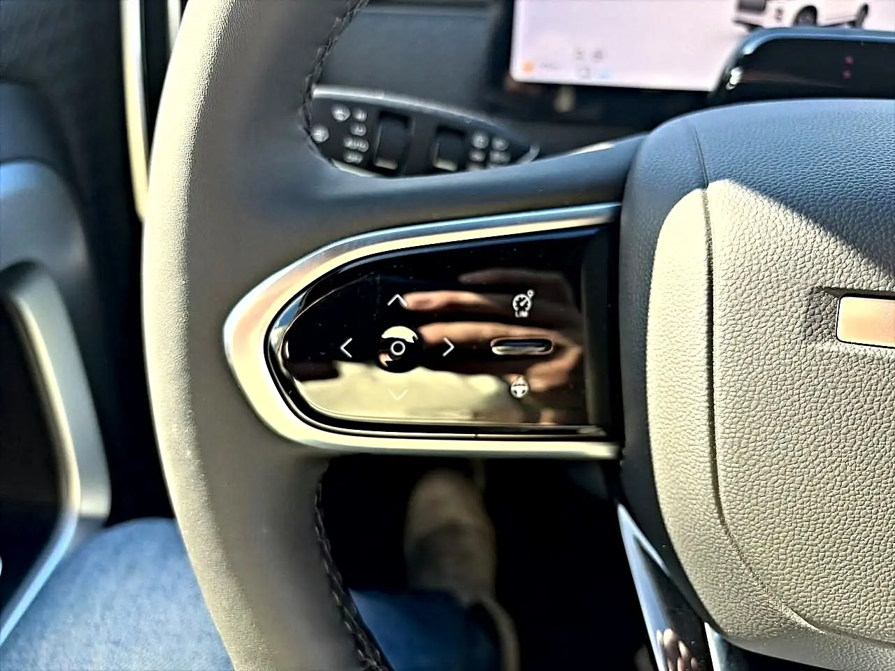 Gros plan sur les commandes multifonctions à gauche du volant noir du JAECOO J7 blanc kaki, intérieur moderne.