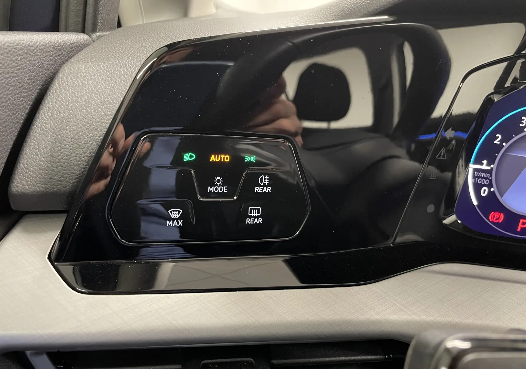 Panneau de commandes d'éclairage et désembuage sur tableau de bord noir brillant d'une Volkswagen Golf 2023.