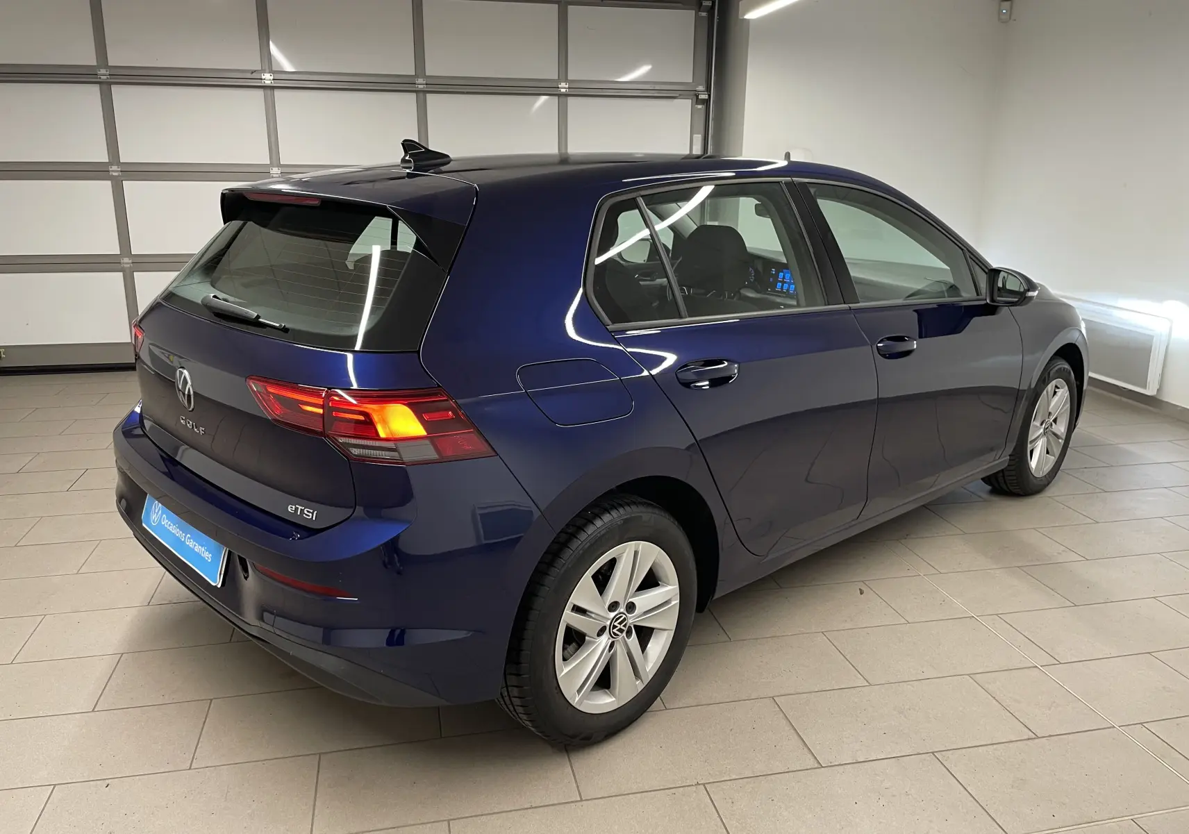 Volkswagen Golf 1.0 TSI 110 DSG7 Life Plus bleu Atlantique vue 3/4 arrière droit en intérieur showroom.