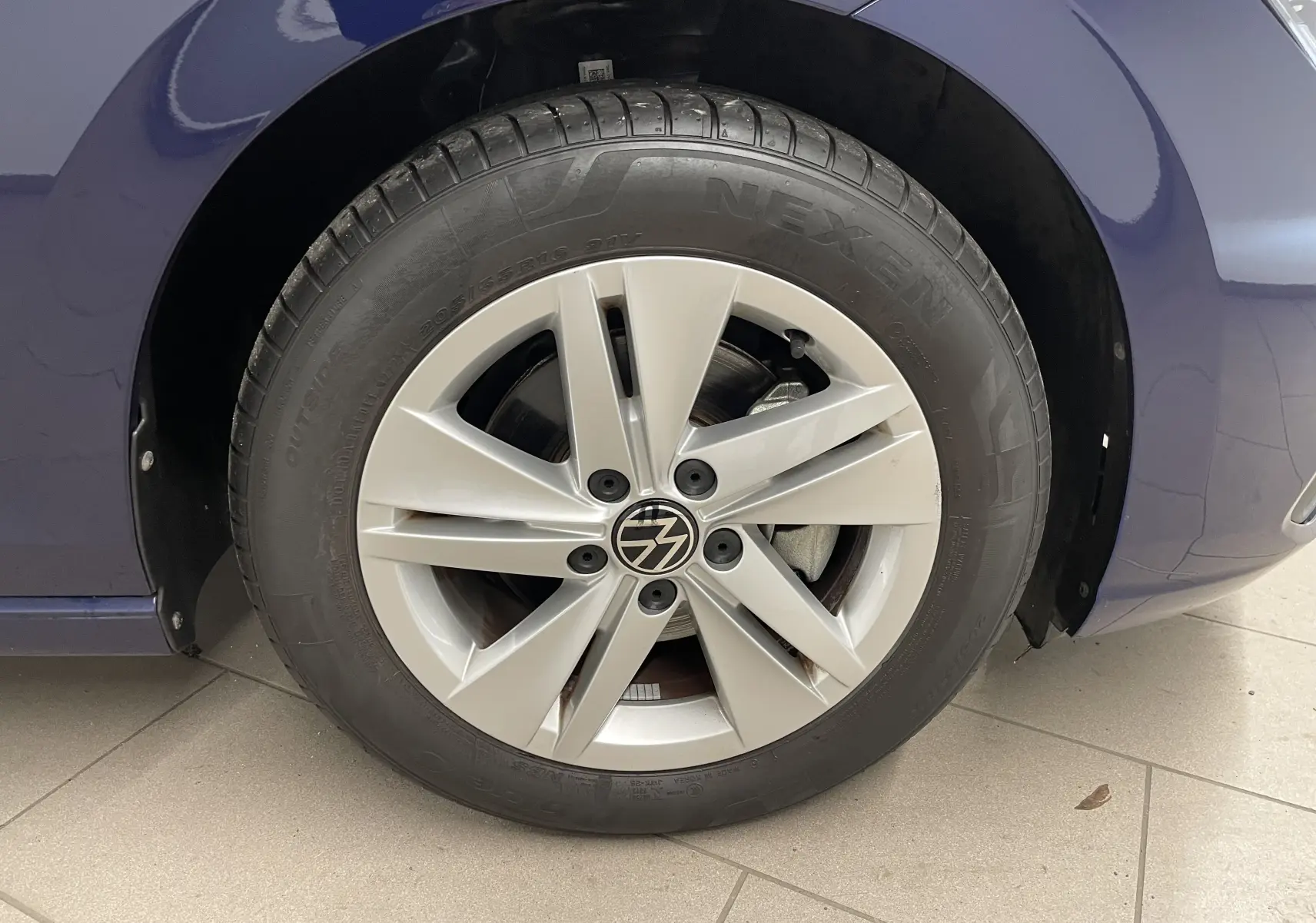 Gros plan sur la roue avant droite d'une Volkswagen Golf 2023 bleu Atlantique avec jante alliage à cinq branches.