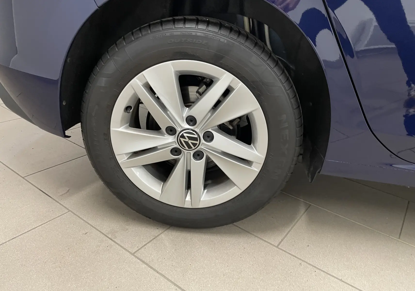 Gros plan sur la roue avant gauche d'une Volkswagen Golf 2023 Bleu Atlantique avec jante alliage argentée.