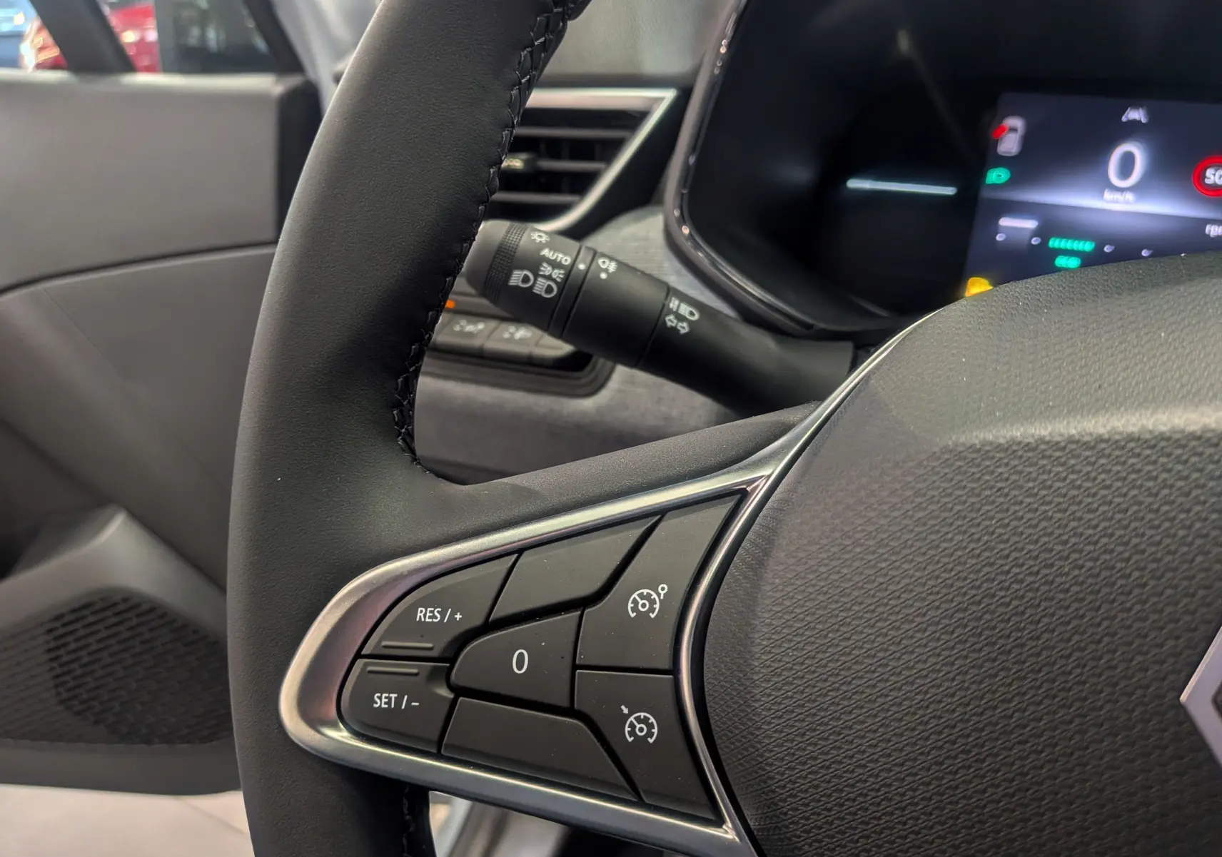 Gros plan sur le volant côté gauche de la Renault Clio V 2025 gris Rafale, avec commandes de régulateur de vitesse visibles.