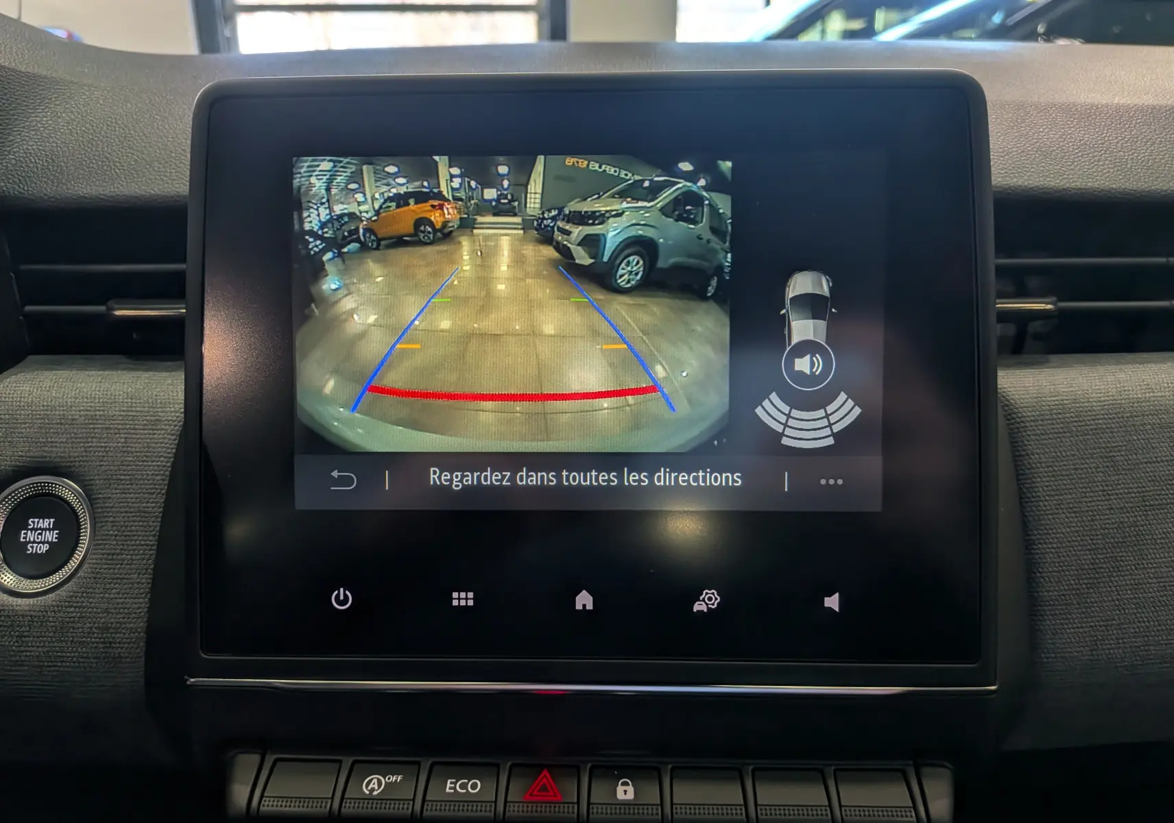 Écran central de la Renault Clio V gris Rafale montrant la caméra de recul avec lignes de guidage et alertes sonores.