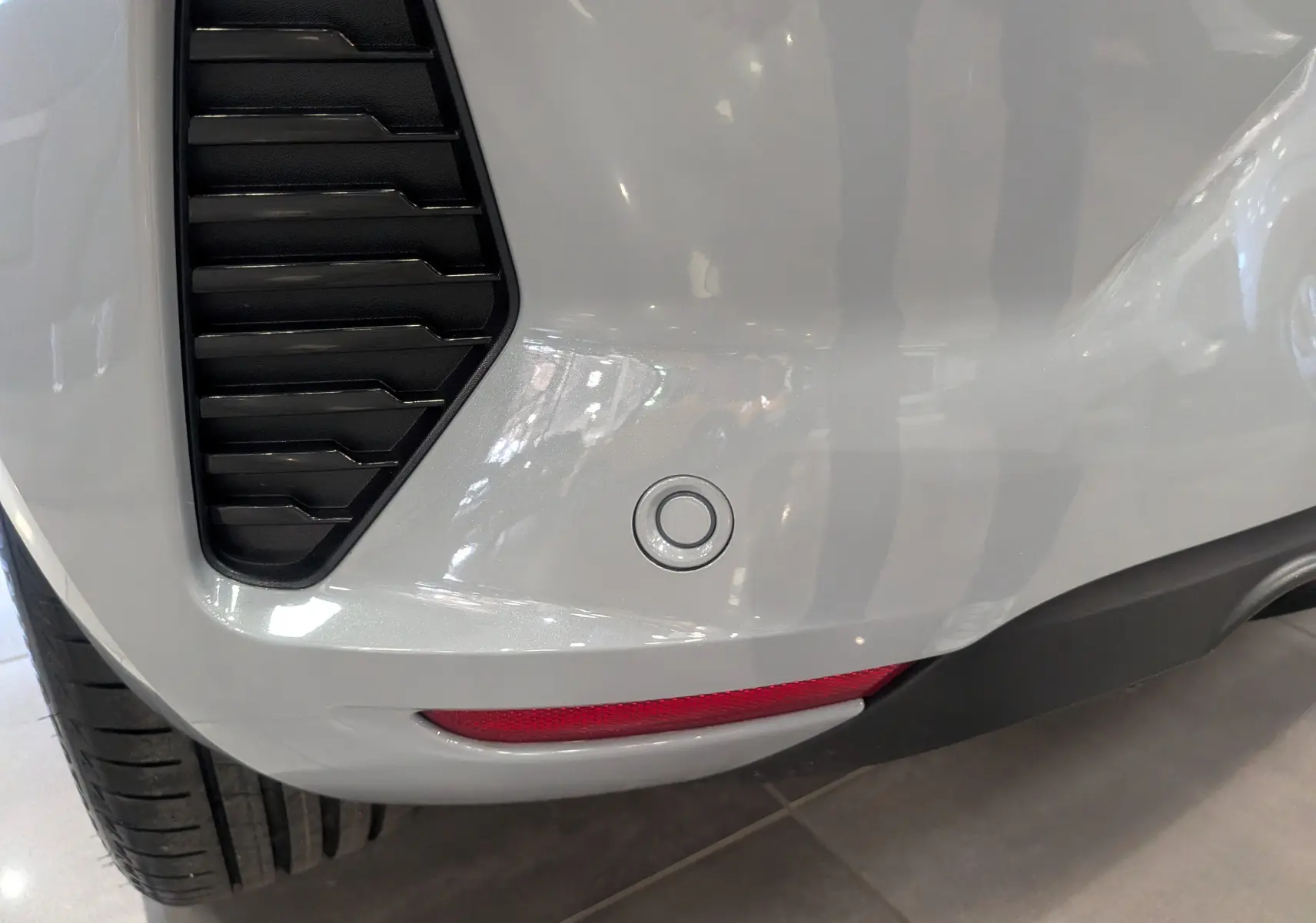 Gros plan sur le pare-chocs arrière gris Rafale de la Renault Clio V avec capteur de recul et feu réfléchissant.