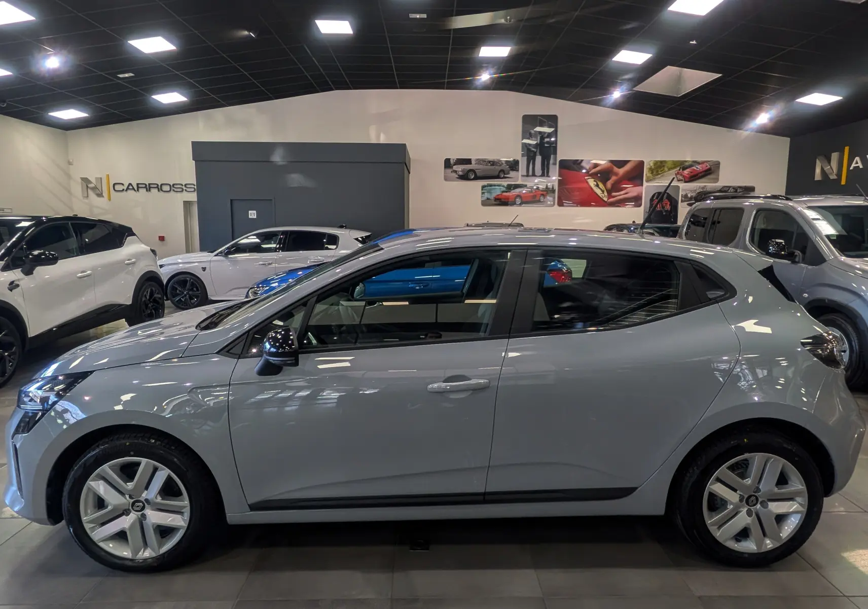 Profil côté gauche de la Renault Clio V 2025 gris Rafale, avec jantes alliage et poignées de porte intégrées au design.