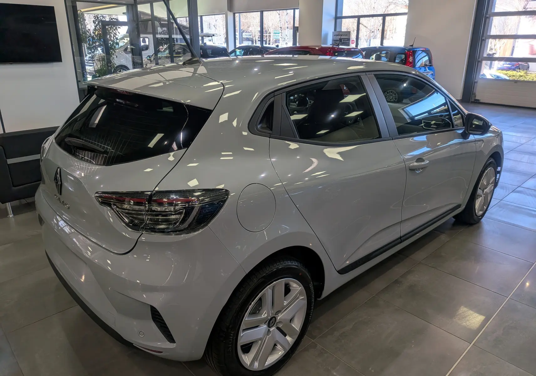 Vue 3/4 arrière droite d'une Renault Clio V gris Rafale en showroom, avec feux arrière LED et jantes alliage.