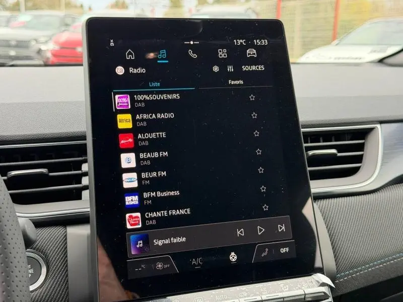 Écran tactile central du tableau de bord du Renault Captur 2026, affichant les stations radio en intérieur noir et bleu.