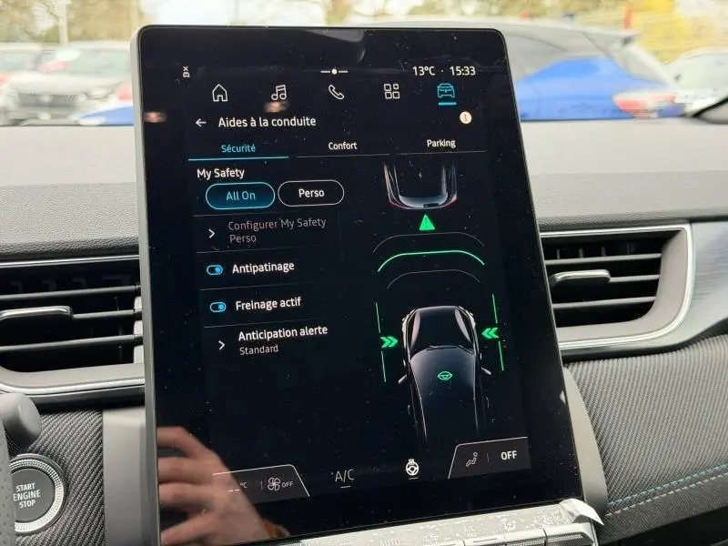 Écran tactile central du Renault Captur 2026 montrant les aides à la conduite, intérieur noir avec surpiqûres bleues.